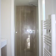 La salle de bain du mobile home bermudes trio est spacieuse. Elle est dotée d'une grande douche et d'un sèche serviette